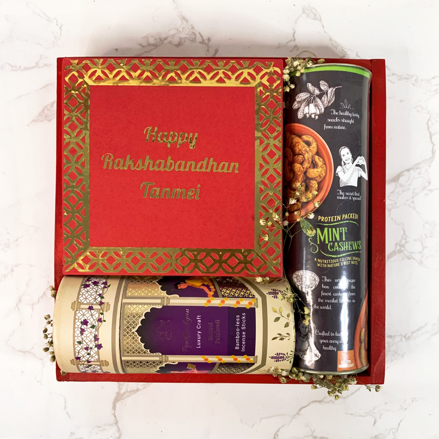 Assortment of products in a vibrant red festive hamper with flavoured dry fruits, aromatherapy incense sticks and mithai scented candles