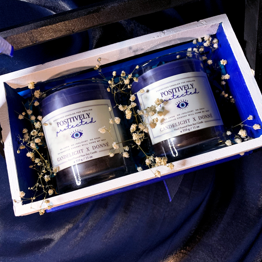 Set of two scented container candles with four fragrances in a wooden gift tray with evil eye labels and baby's breath flowers for decoration