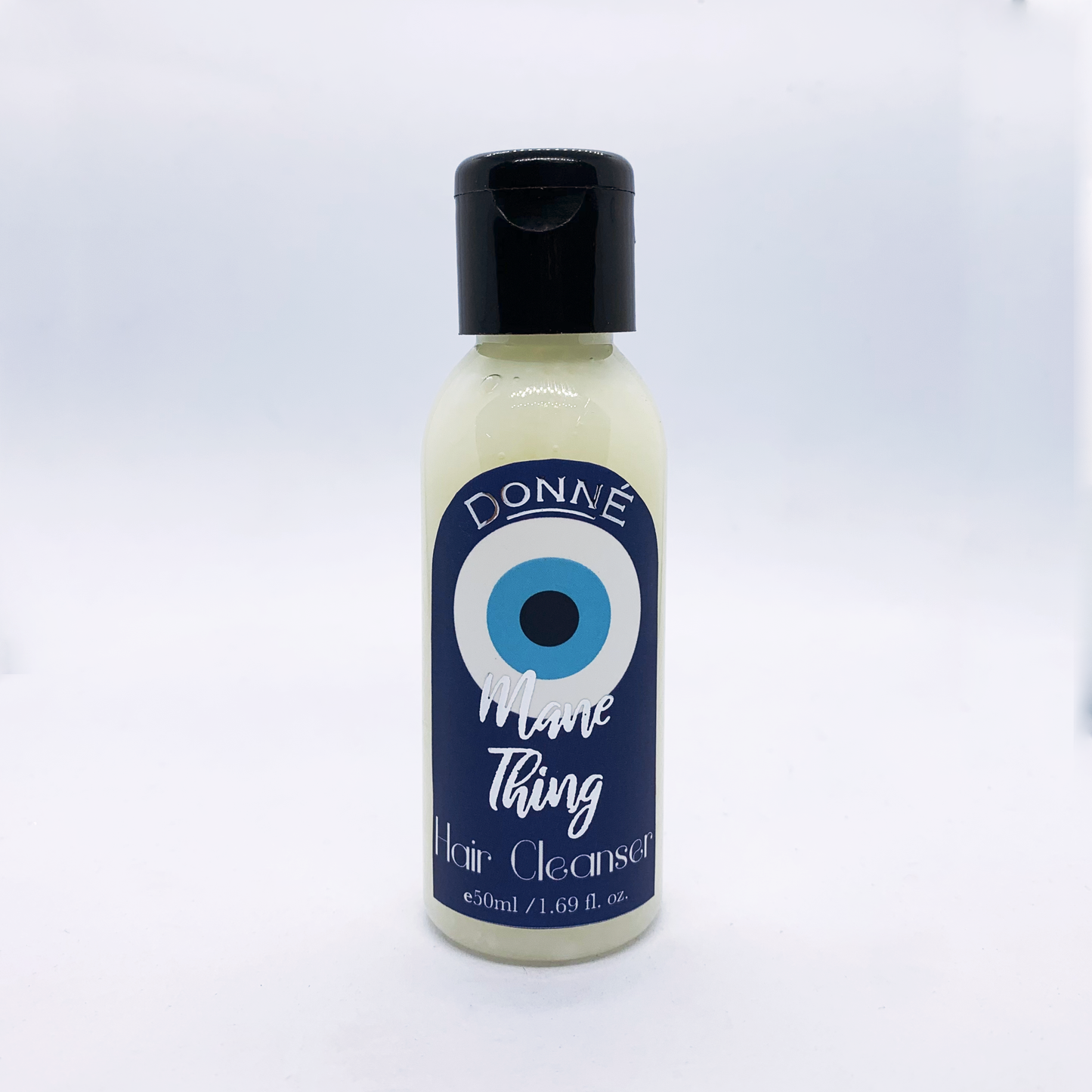 Mane Thing - a shampoo against a white background with a black lid, evil eye labels with silver accents