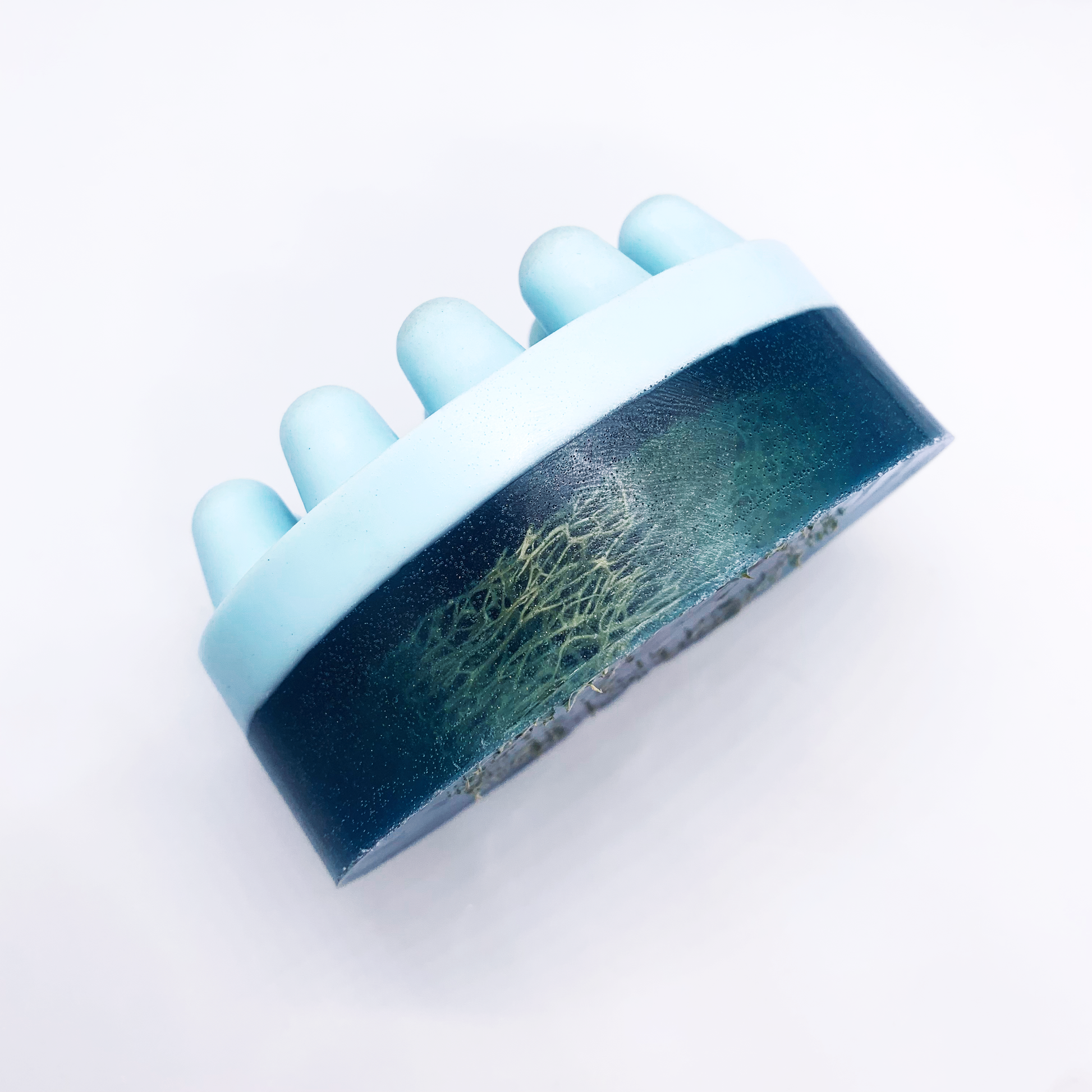 A side view of the blue Mixology soap with massage action in the front and an embedded loofah at the back