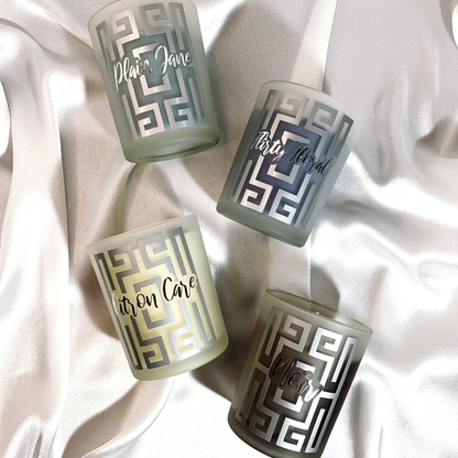 Decorative overview of scented candles with greek based inspiration and metallic label and fragrance name on satin