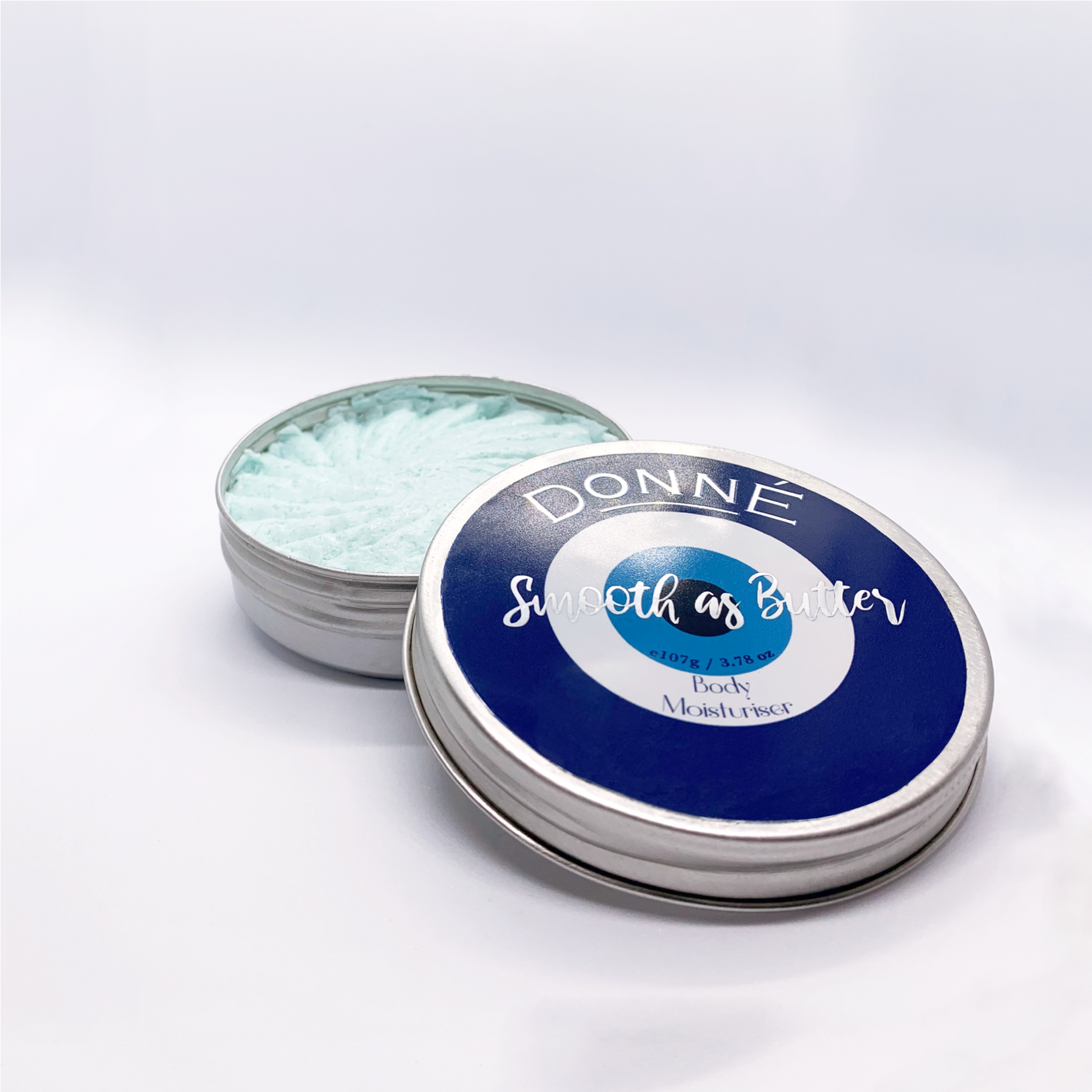 Round container with evil eye label and metallic accents for rich light blue hand and body butter based lotion with a milky decorative texture