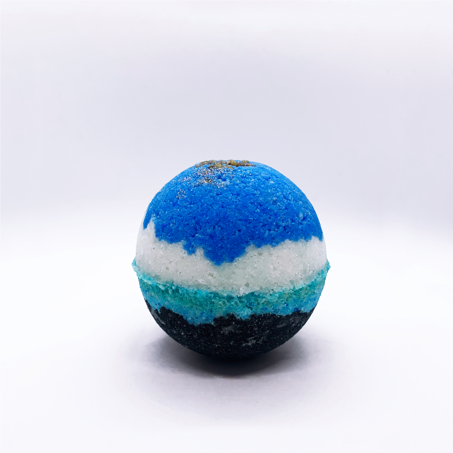 Multilayered Epsom salt and baking soda based fizzy bath bomb in blue, white, turquoise and black and lavender buds on top